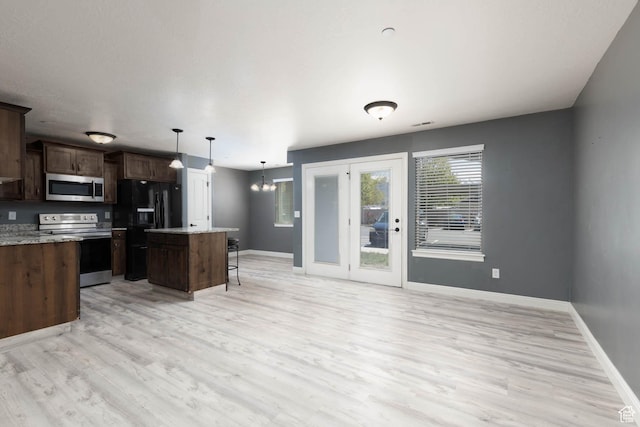 kitchen with baseboards, light wood-style floors, appliances with stainless steel finishes, and a center island