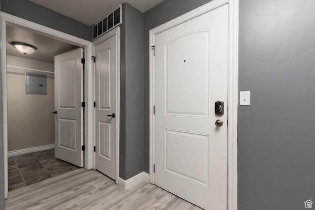 foyer with electric panel, baseboards, and visible vents