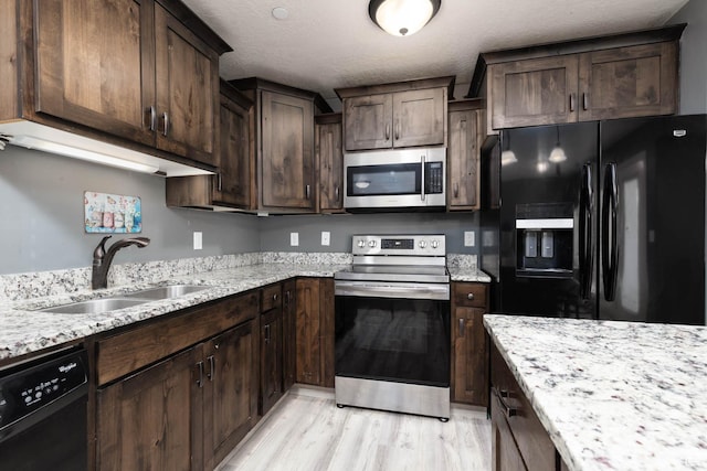 kitchen featuring black appliances, light wood-style floors, a sink, and dark brown cabinetry