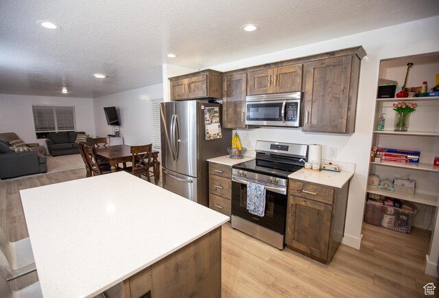 1511 S Sageberry Dr, Santaquin, UT 84655 - kitchen featuring stainless steel appliances, light countertops, light wood finished floors, a textured ceiling, and open floor plan