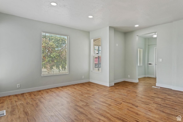 unfurnished room featuring light wood-type flooring, visible vents, baseboards, and recessed lighting