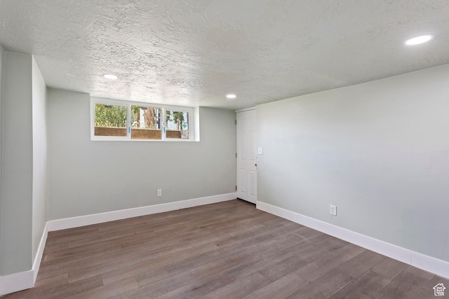 spare room with wood finished floors, baseboards, and recessed lighting