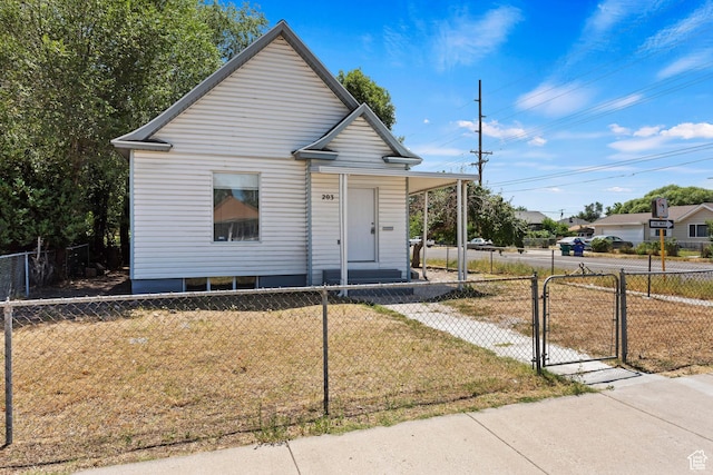 bungalow-style home with a gate, a front yard, covered porch, and a fenced front yard
