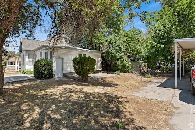 view of yard with fence, a carport, and concrete driveway