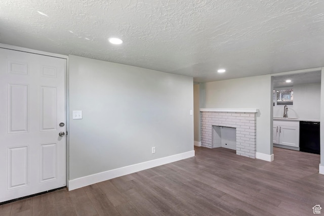 unfurnished living room with baseboards, a textured ceiling, a sink, and wood finished floors