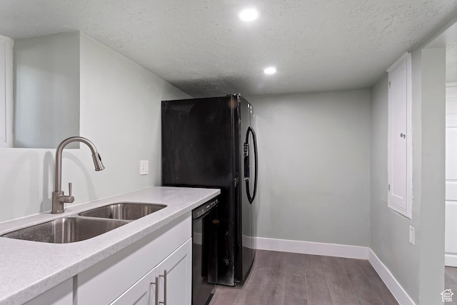 kitchen with a textured ceiling, black appliances, dark wood finished floors, and a sink