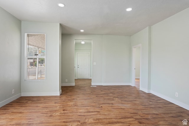 empty room featuring recessed lighting, baseboards, and wood finished floors
