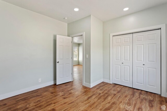 unfurnished bedroom with recessed lighting, baseboards, a closet, and wood finished floors