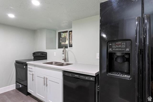 kitchen with a sink, white cabinetry, dark wood-style flooring, black appliances, and light countertops