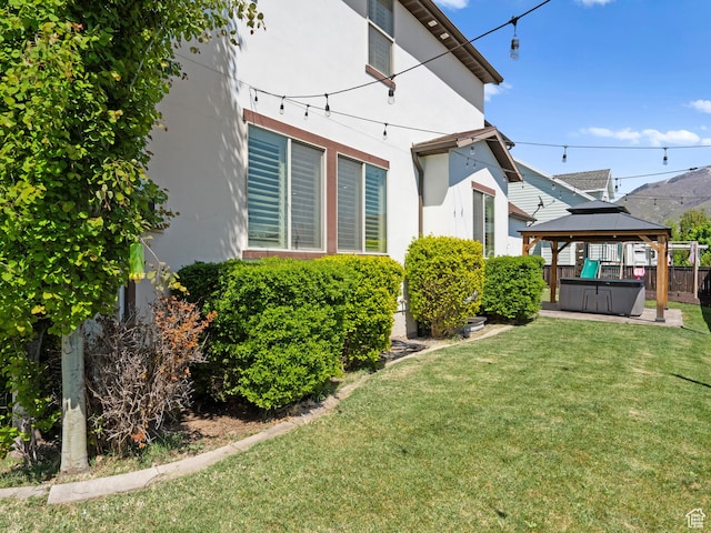 1827 W Burke Ln, Farmington, UT 84025 - back of house featuring a hot tub, stucco siding, a lawn, and a gazebo