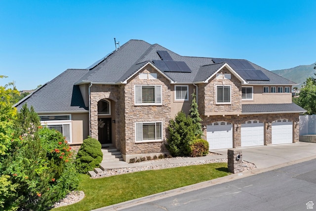 2247 Country Oaks Dr, Layton, UT 84040 - view of front of home with stone siding, driveway, an attached garage, and roof mounted solar panels