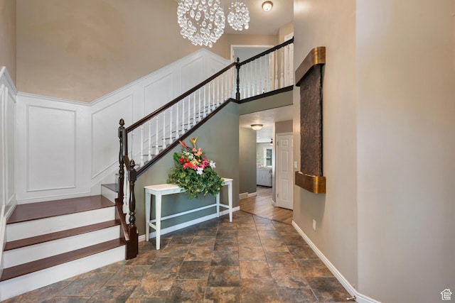2247 Country Oaks Dr, Layton, UT 84040 - stairway with stone finish floors, a chandelier, and a decorative wall
