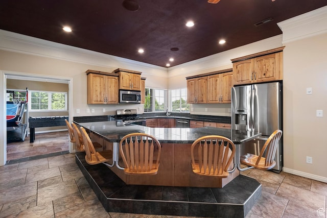 2247 Country Oaks Dr, Layton, UT 84040 - kitchen featuring stainless steel appliances, crown molding, healthy amount of natural light, a breakfast bar area, and brown cabinets