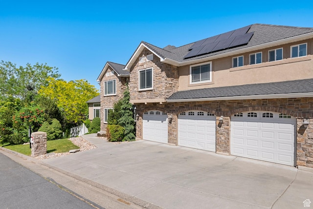 2247 Country Oaks Dr, Layton, UT 84040 - view of front facade featuring stone siding, driveway, a garage, solar panels, and stucco siding