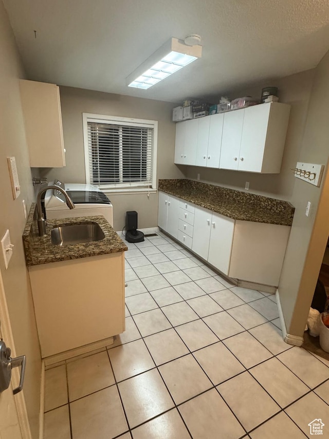 2247 Country Oaks Dr, Layton, UT 84040 - kitchen with light tile patterned floors, baseboards, a sink, white cabinetry, and dark stone countertops