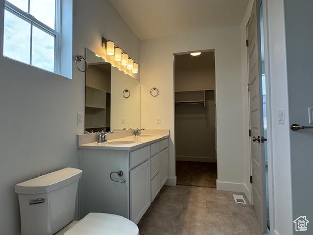 full bathroom with toilet, visible vents, double vanity, and a sink