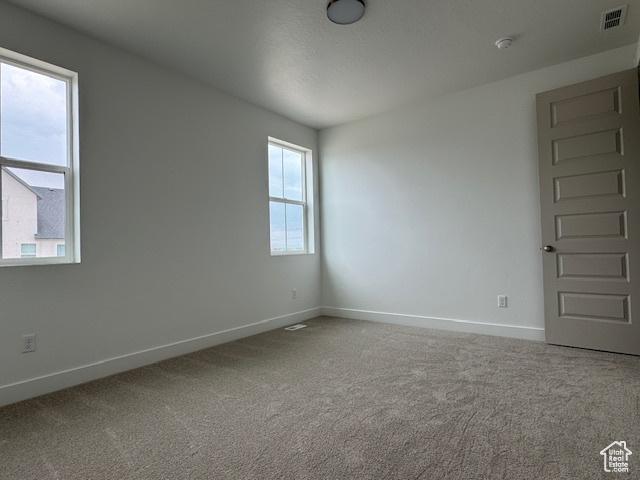 unfurnished room with baseboards, visible vents, and carpet
