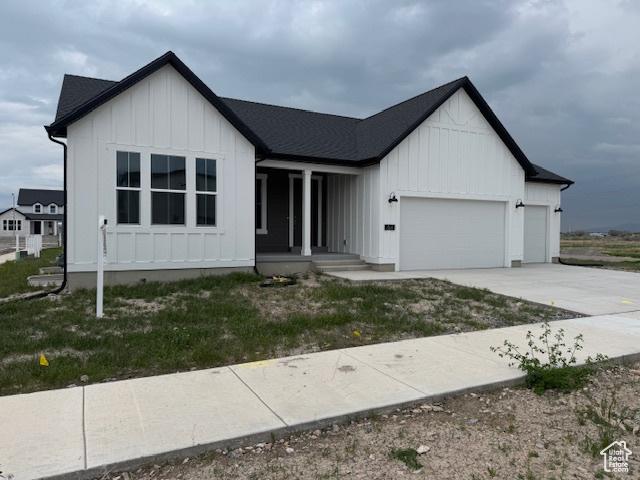 view of front facade featuring covered porch, concrete driveway, a garage, and board and batten siding