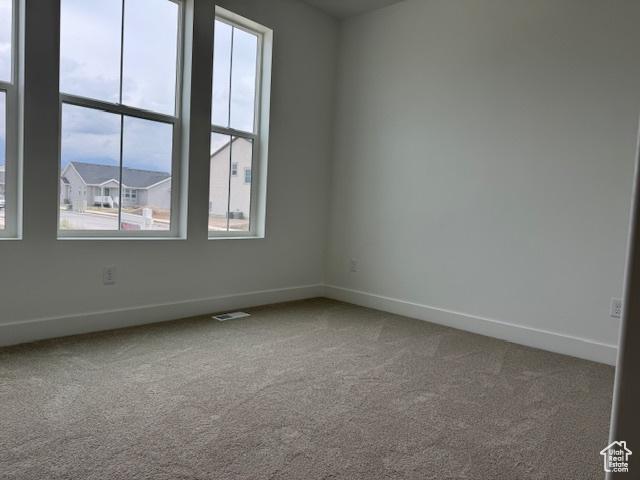 carpeted spare room featuring baseboards and visible vents