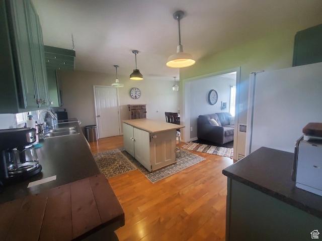 kitchen with a sink, freestanding refrigerator, light wood-style flooring, and pendant lighting