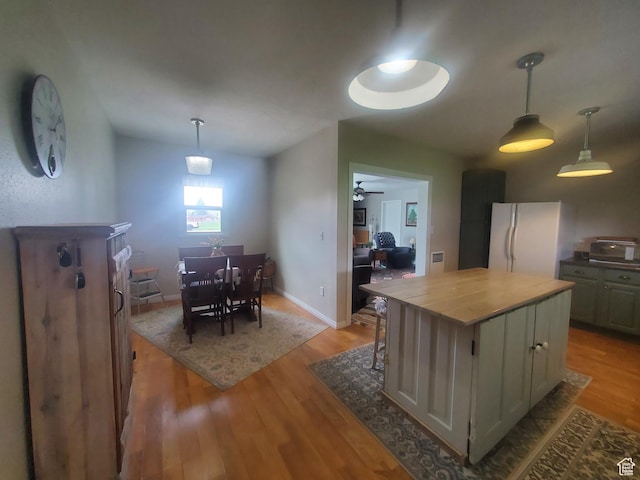 kitchen featuring a center island, freestanding refrigerator, pendant lighting, ceiling fan, and light wood-style floors