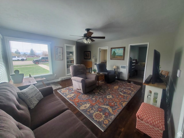 living area with baseboards, ceiling fan, visible vents, and wood finished floors