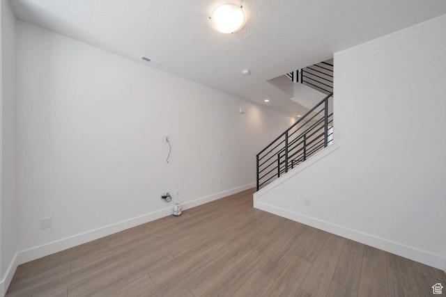 unfurnished living room featuring visible vents, wood finished floors, baseboards, and stairs
