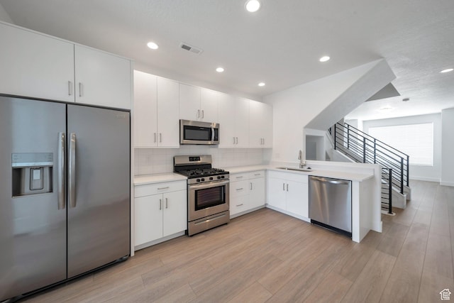 kitchen featuring light countertops, stainless steel appliances, light wood-type flooring, and a sink