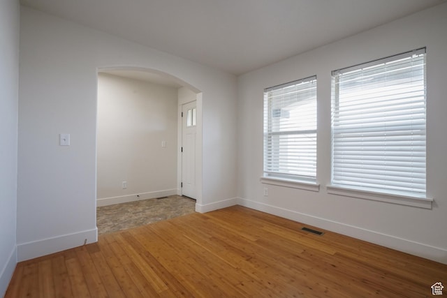 235 E Caracara St S, Saratoga Springs, UT 84043 - empty room with light wood-style flooring, arched walkways, baseboards, and visible vents