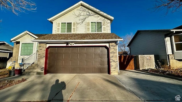 traditional-style house featuring brick siding, driveway, fence, and a garage