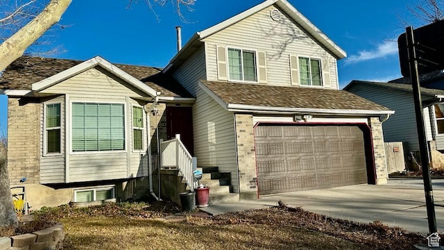 split level home featuring an attached garage, a shingled roof, and driveway