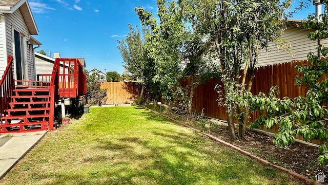 view of yard with a fenced backyard, a wooden deck, and stairway