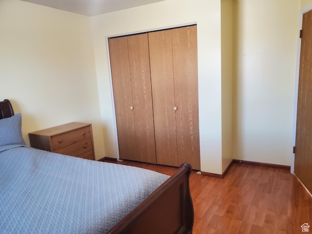 bedroom with a closet, light wood-style flooring, and baseboards