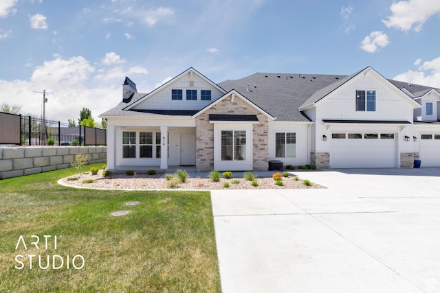 view of front of property featuring stone siding, a garage, fence, a front lawn, and driveway
