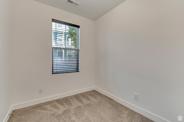 spare room featuring light colored carpet, visible vents, baseboards, and lofted ceiling