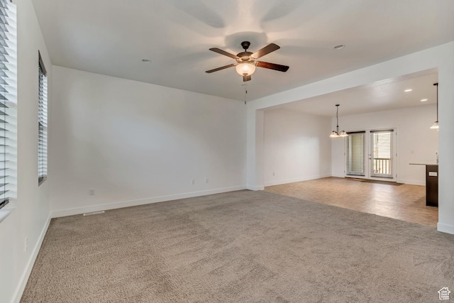 unfurnished room with carpet flooring, baseboards, ceiling fan with notable chandelier, and recessed lighting