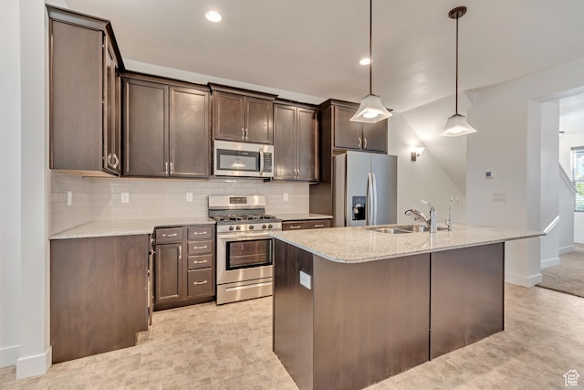 kitchen with light stone countertops, dark brown cabinets, a sink, decorative backsplash, and appliances with stainless steel finishes