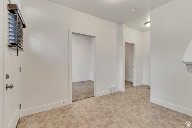 empty room with baseboards, light floors, and visible vents