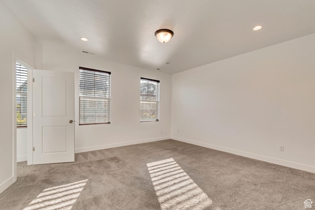 unfurnished room with carpet, visible vents, and baseboards