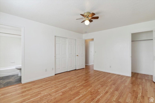 3035 N 2575 W, Farr West, UT 84404 - unfurnished bedroom featuring multiple closets, baseboards, ensuite bath, and light wood-type flooring