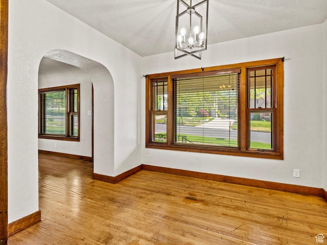 1362 Marilyn Dr, Ogden, UT 84403 - unfurnished room featuring arched walkways, wood finished floors, baseboards, and a chandelier