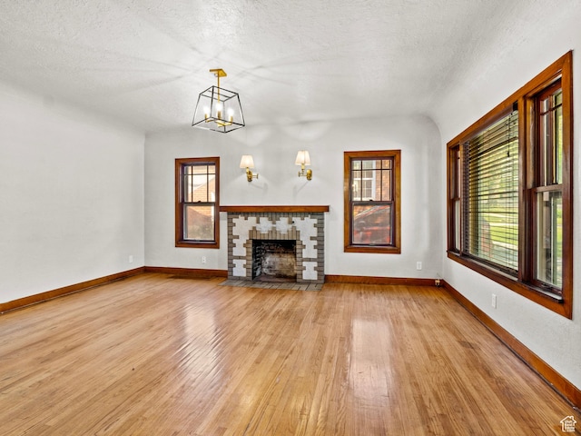 1362 Marilyn Dr, Ogden, UT 84403 - unfurnished living room featuring light wood finished floors, plenty of natural light, baseboards, a fireplace with flush hearth, and a textured ceiling