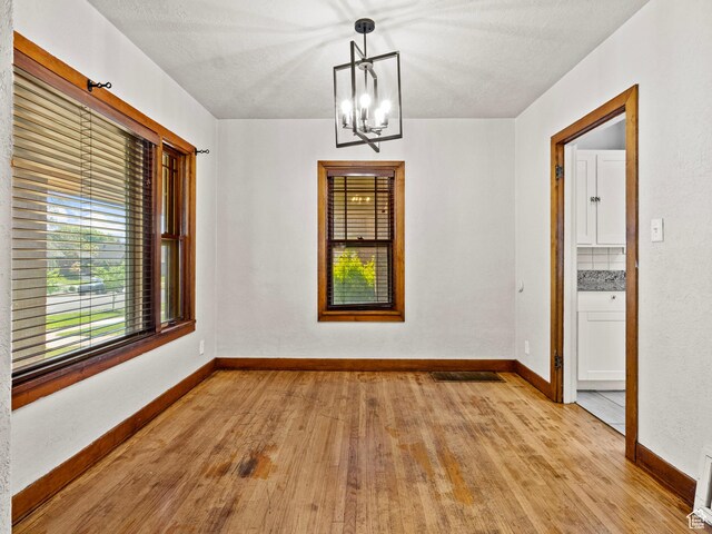 1362 Marilyn Dr, Ogden, UT 84403 - unfurnished dining area with light wood-style flooring, a chandelier, and baseboards