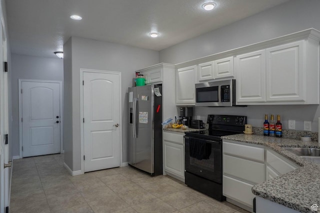 kitchen featuring light tile patterned floors, a sink, stainless steel appliances, white cabinets, and baseboards