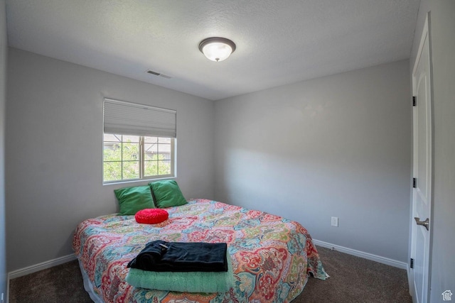 bedroom featuring baseboards, a textured ceiling, visible vents, and carpet floors