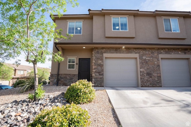 view of property featuring stone siding, stucco siding, an attached garage, and driveway