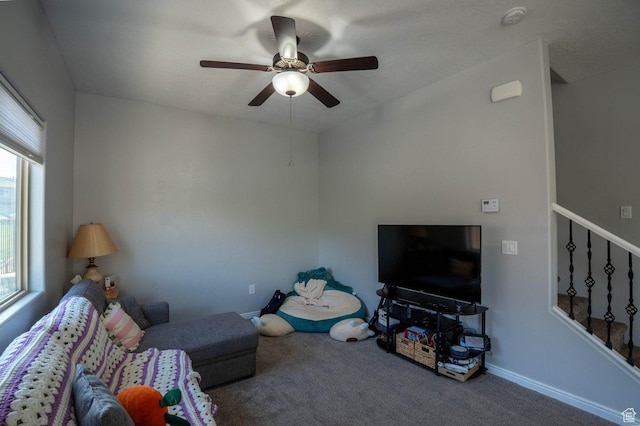unfurnished living room with a ceiling fan, carpet flooring, baseboards, and stairway