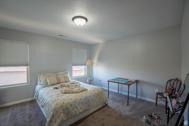 carpeted bedroom featuring a textured ceiling, visible vents, and baseboards