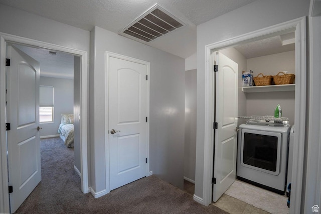clothes washing area with washer / clothes dryer, light colored carpet, baseboards, and visible vents
