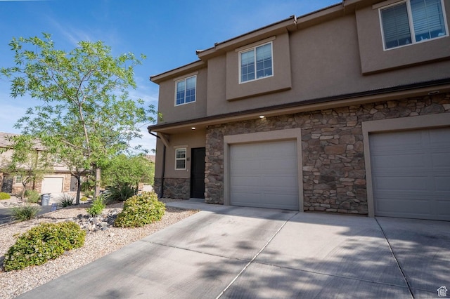 townhome / multi-family property with concrete driveway, an attached garage, stucco siding, and stone siding